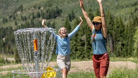Two friends celebrating while playing disc golf at Solitude Mountain Resort
