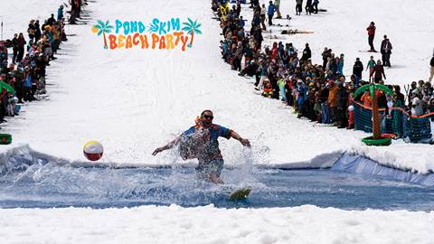 Snowboarder attempting the Pond Skim at Solitude