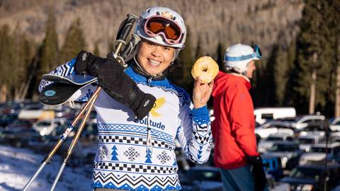 Guest in a Solitude sweater holding a donut on opening day