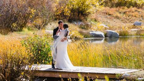 bride and groom embracing on a wooden dock beside a mountain pond at a wedding venue at solitude mountain resort in fall