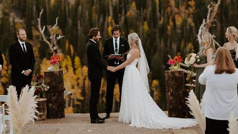 A bride and groom exchange wedding vows in front of a scenic mountain landscape at Solitude Mountain Resort