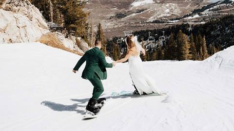 A couple skis and snowboards during a winter wedding at Solitude Mountain Resort
