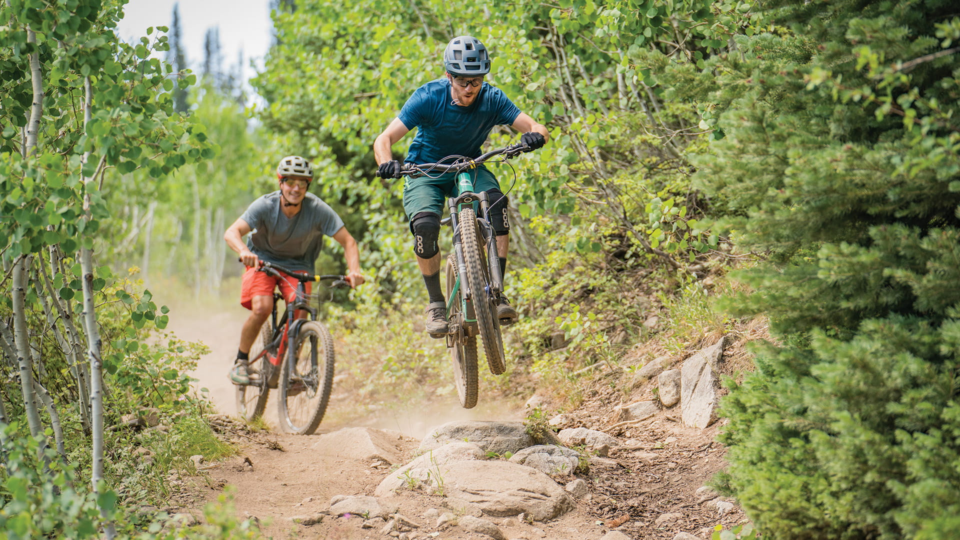 Two bikers jumping over a rock at Solitude Mountain Resort