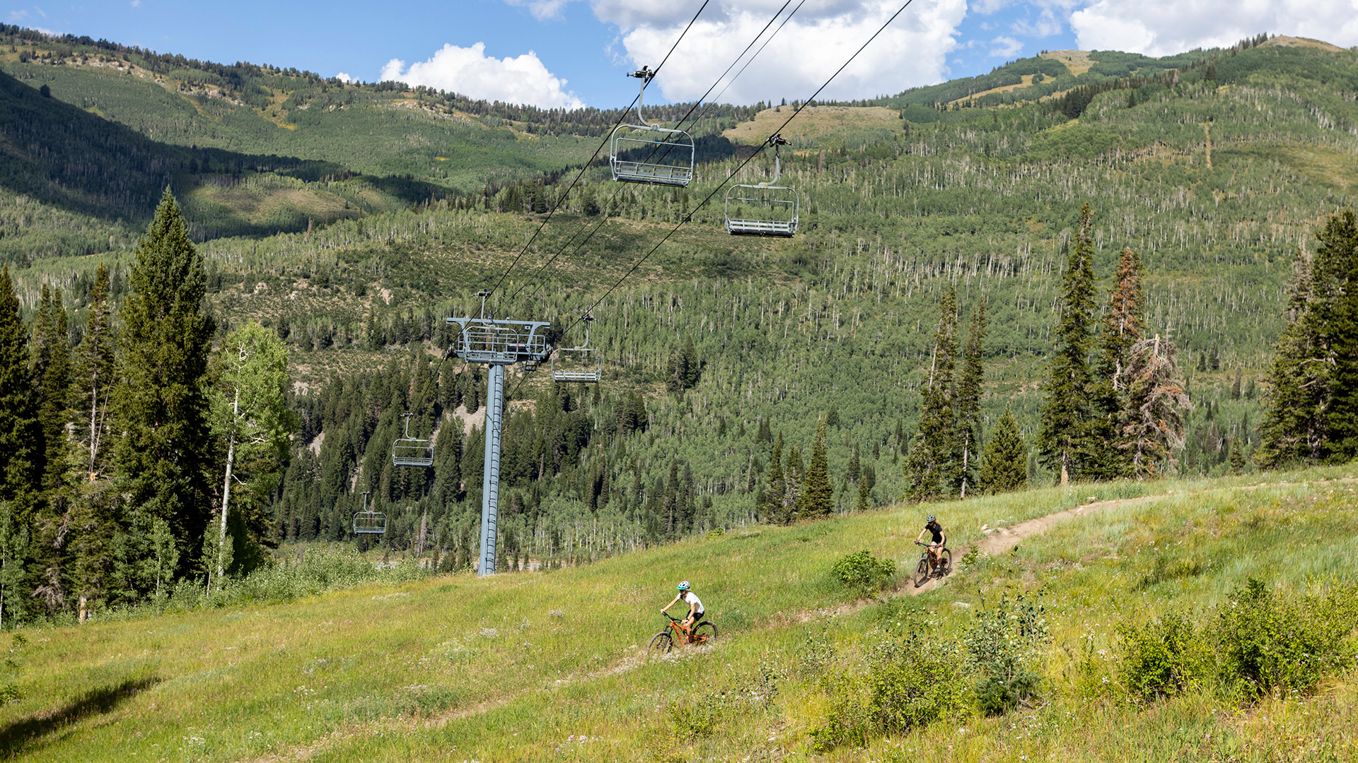 Two mountain bikers biking under Eagle Express at Solitude Mountain Resort