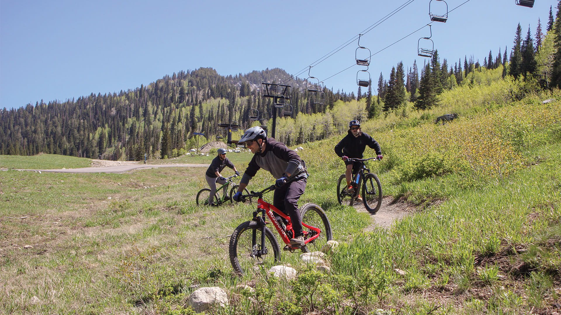 Three mountain bike lesson takers turning on a bike trail at Solitude