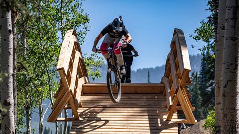 Two riders jumping off a bridge at Solitude Bike Park