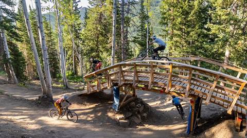 Mountain bikers riding over and under a bridge at Solitude Bike Park