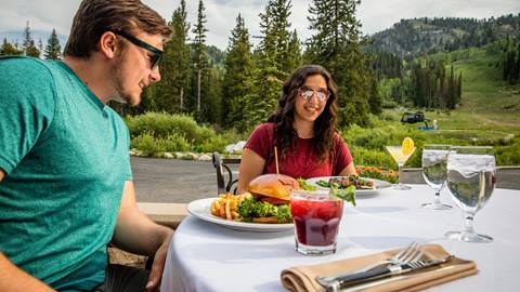 A couple enjoys dinner together on the patio of Honeycomb Grill at Solitude Mountain Resort