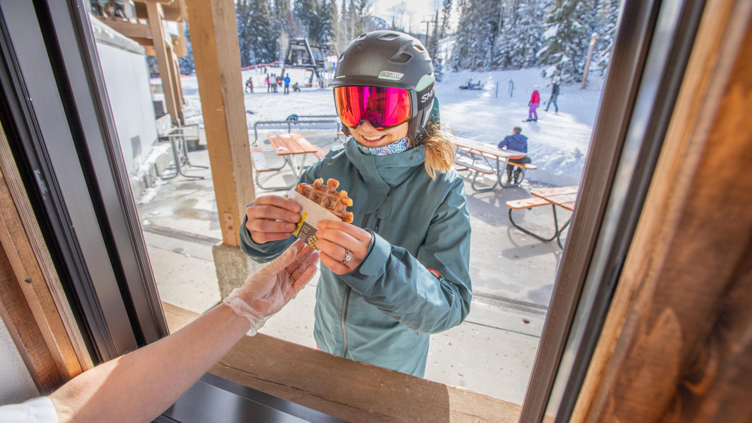 Skier receives a waffle from Little Dollie Waffle window