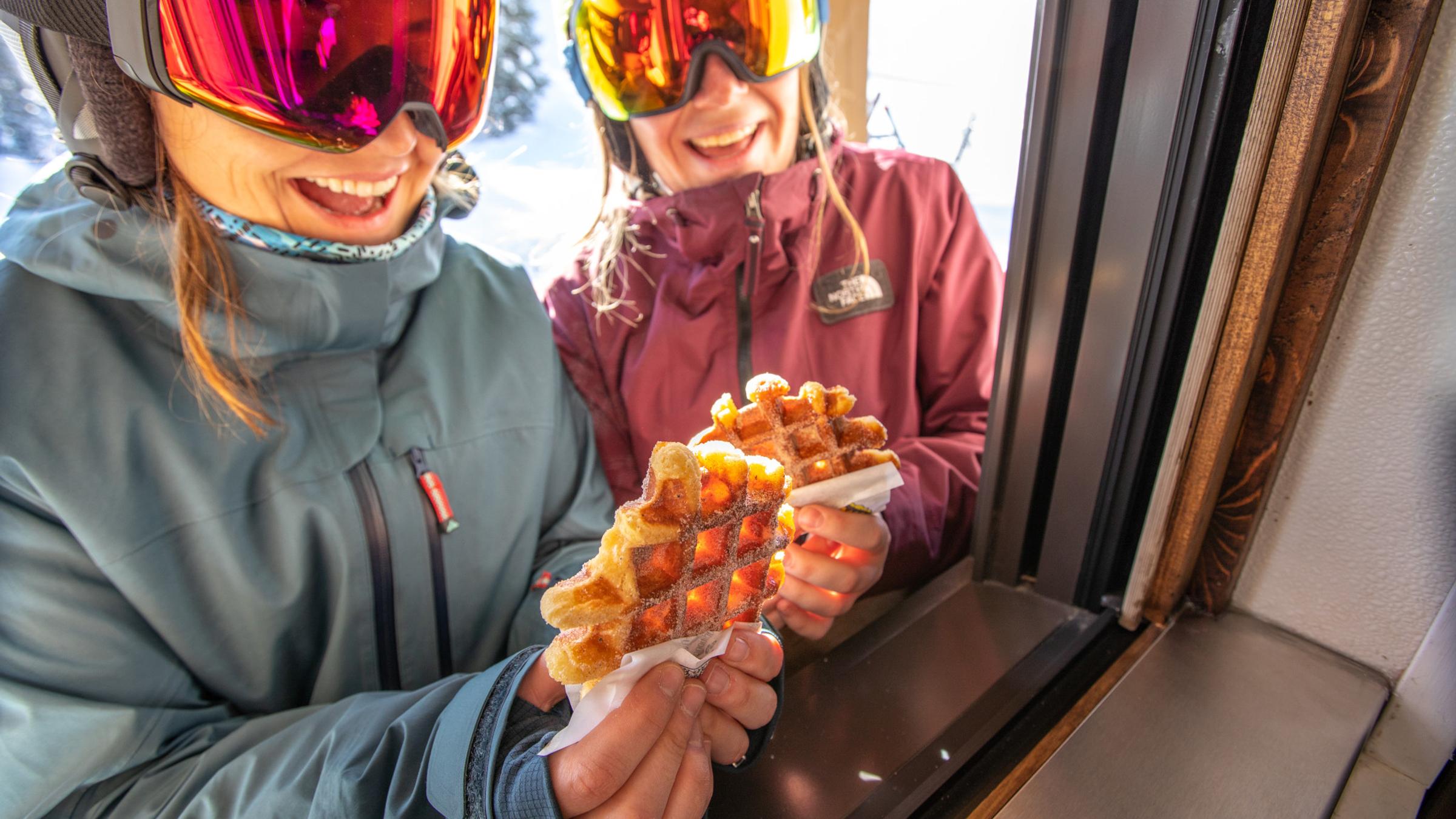 Skiers receiving a waffle from Little Dollie Waffle's window