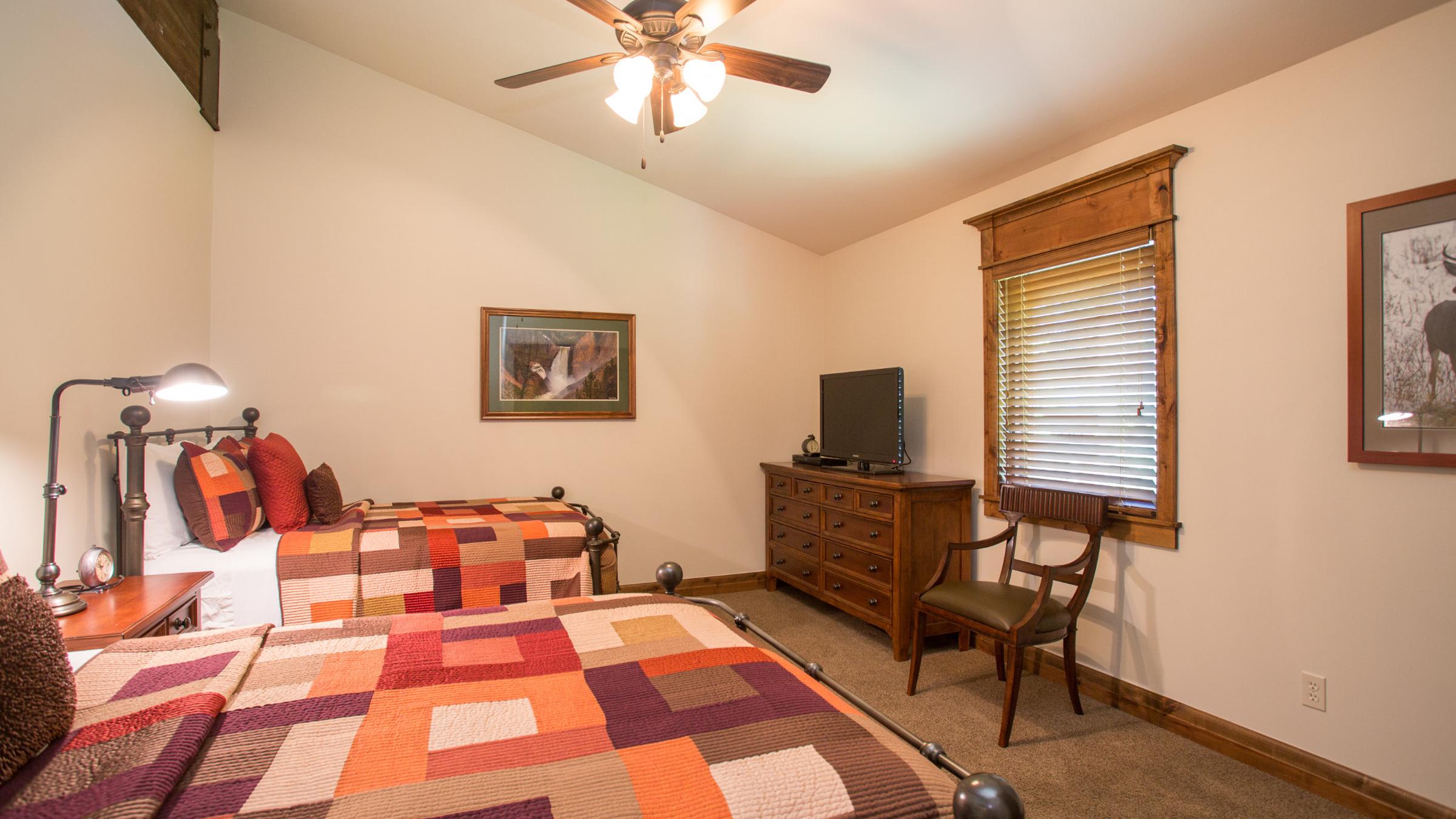 Bedroom with two beds, tv, dresser and chair