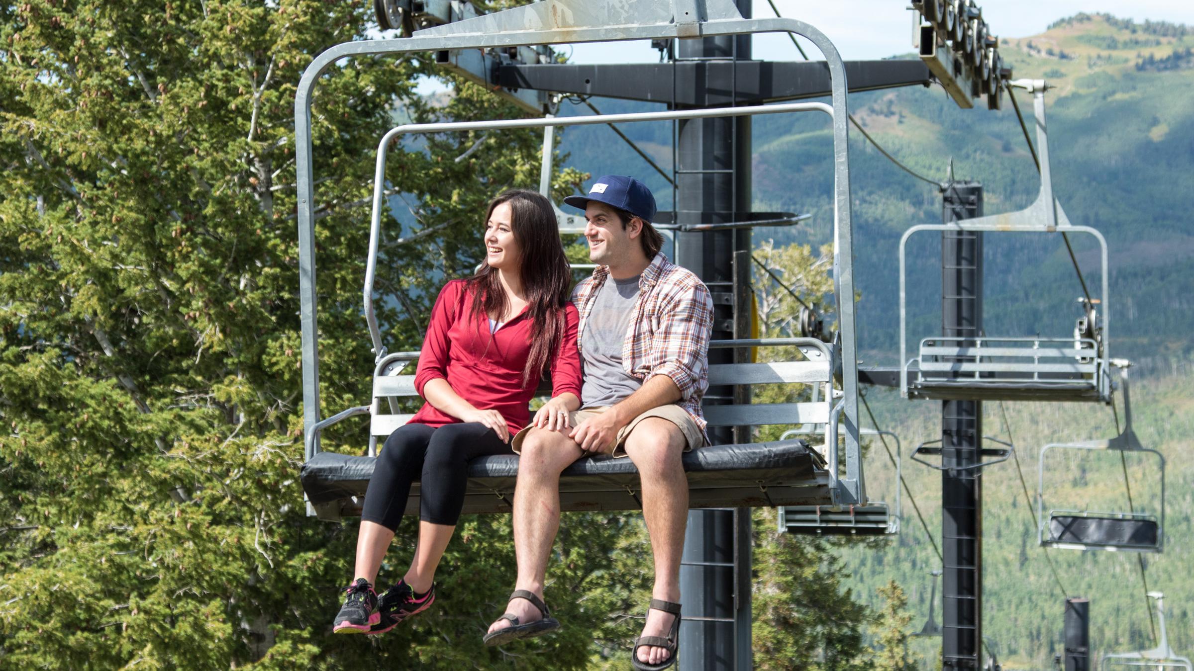 A couple on a chairlift for a summer scenic lift ride up the mountain