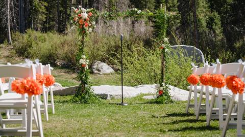 close view of a floral wedding arch and aisle chairs arranged on a grassy lawn at a wedding venue at solitude mountain resort