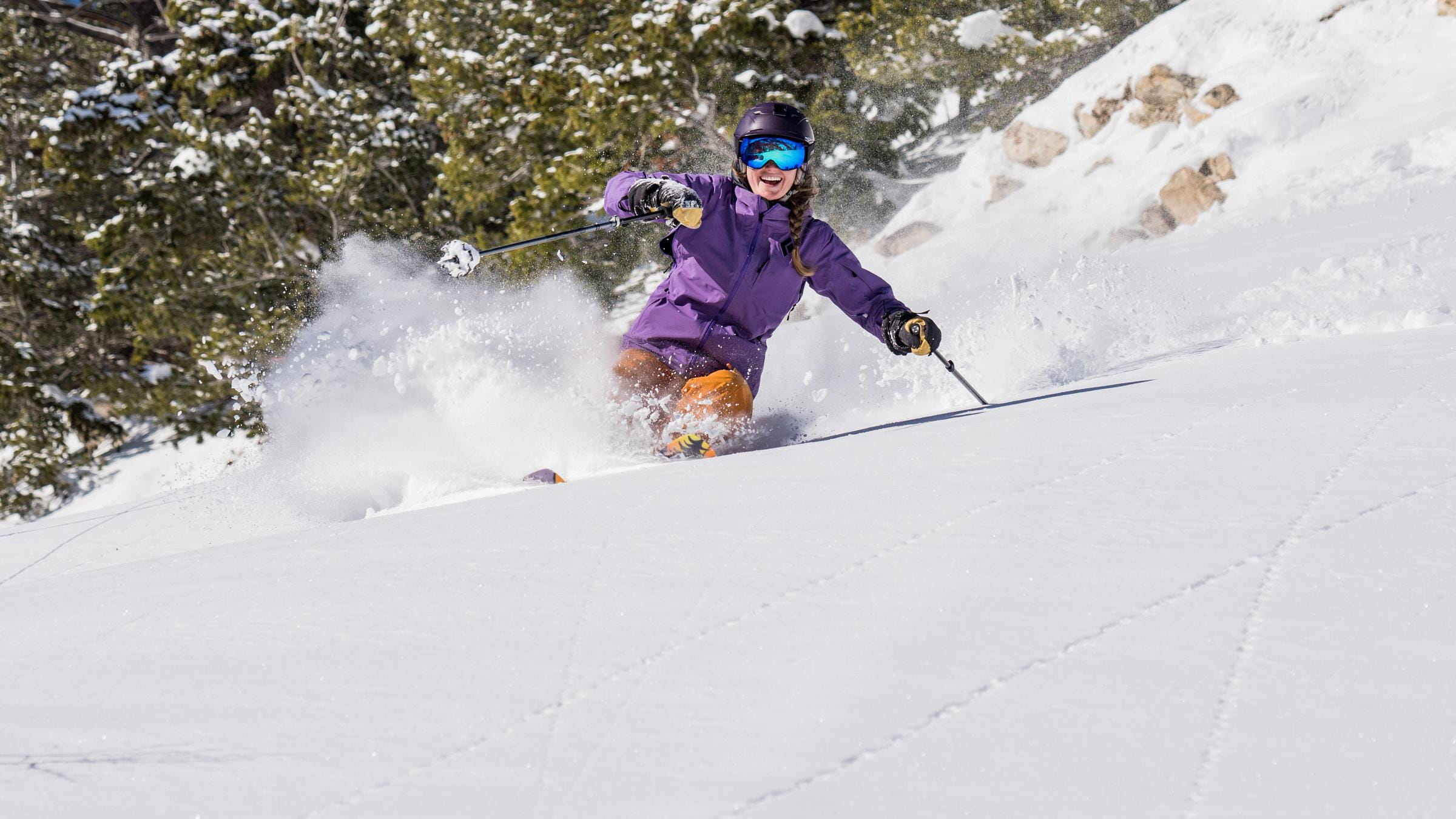 Female skier makes a powder turn under blue skies at Solitude Mountain Resort