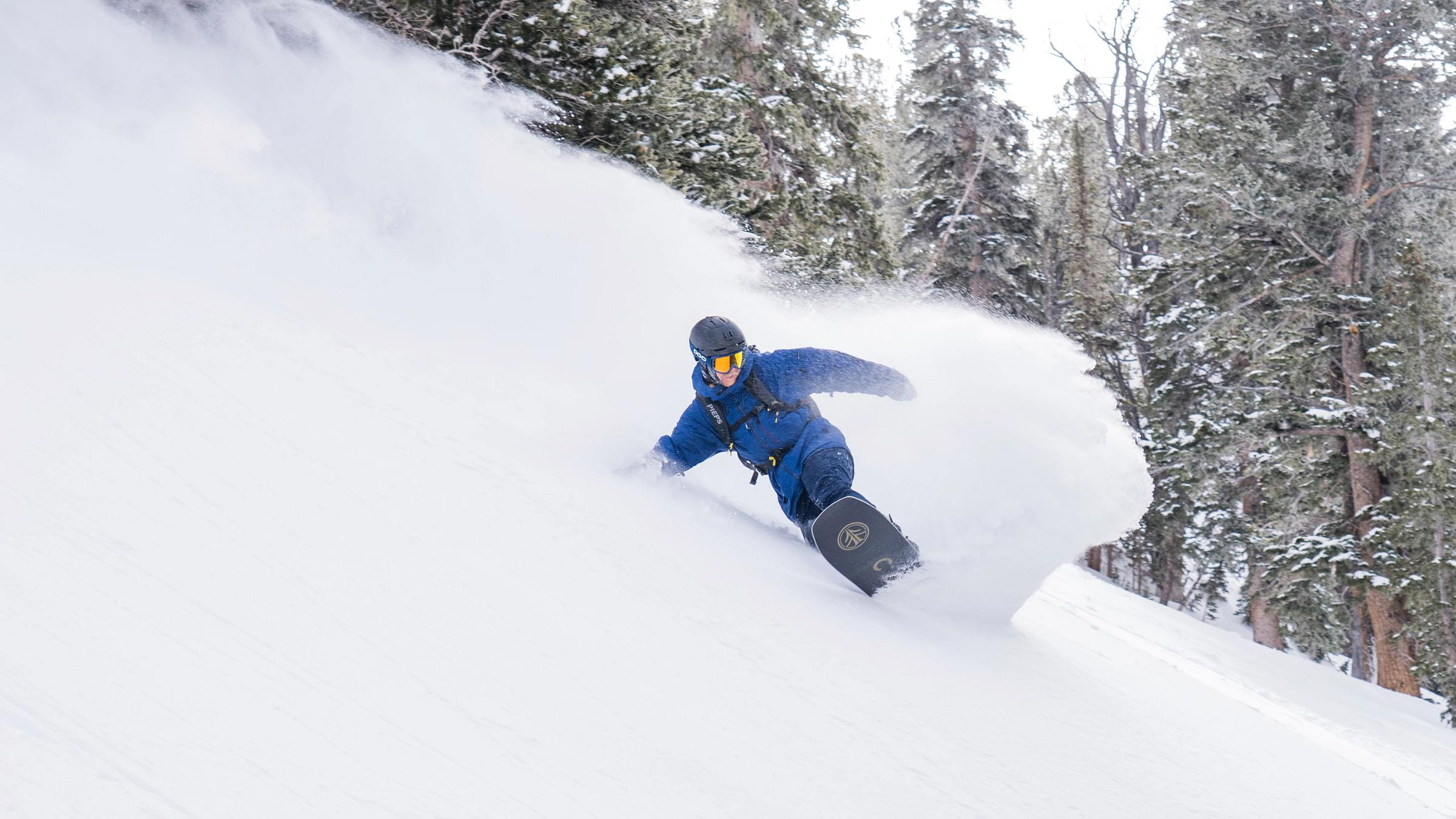 Male snowboarder makes a powder turn in the trees at Solitude Mountain Resort