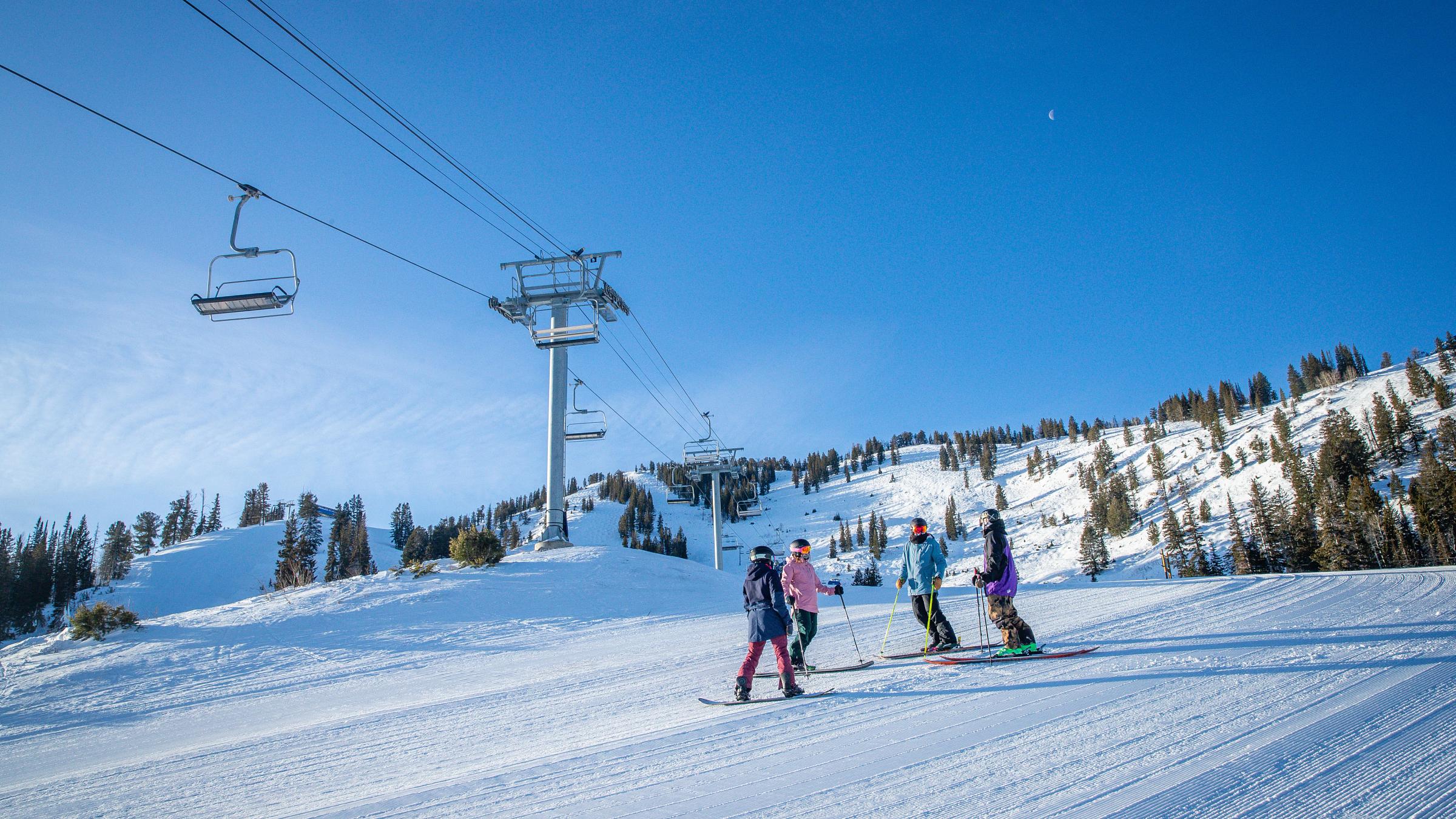 Four friends on skis and snowboard stop to chat on the groomed slopes of Solitude Mountain Resort
