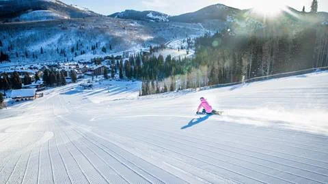 A female skier makes a turn on a perfectly groomed slope at Solitude Mountain Resort
