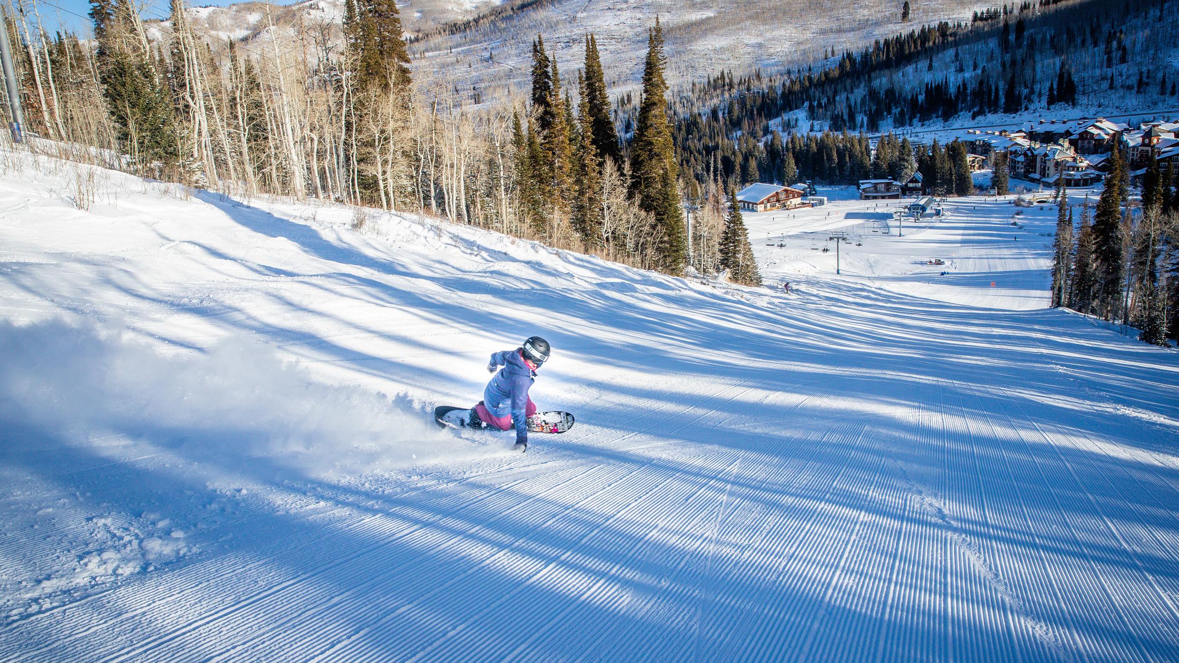 A female snowboarder makes a turn on a perfectly groomed slope at Solitude Mountain Resort